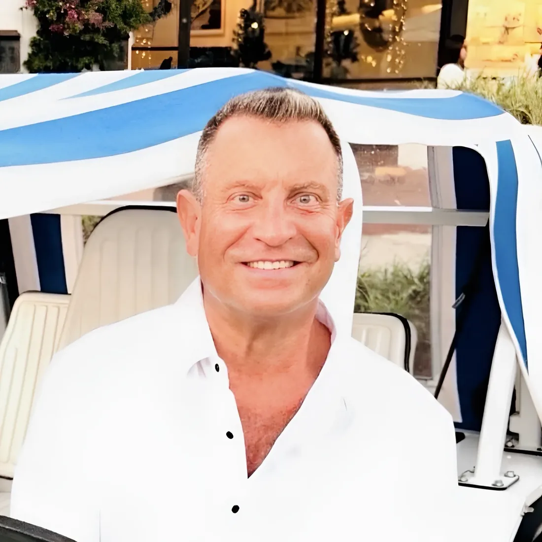 Jim, owner of Naples Golf Cart Rentals FL and MOKE America Naples, smiling in a MOKE on Fifth Avenue South in Naples